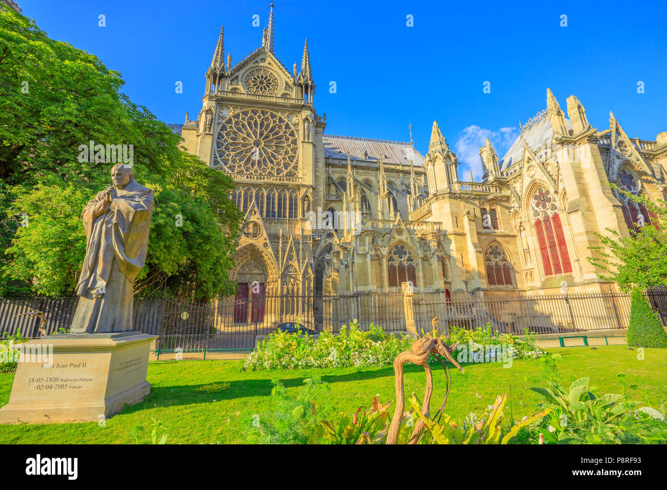 Pope John Paul II statue on side of church Notre Dame of Paris, France. Gothic architecture of Cathedral of Paris, Ile de la cite. Beautiful sunny day in the blue sky. Stock Photo