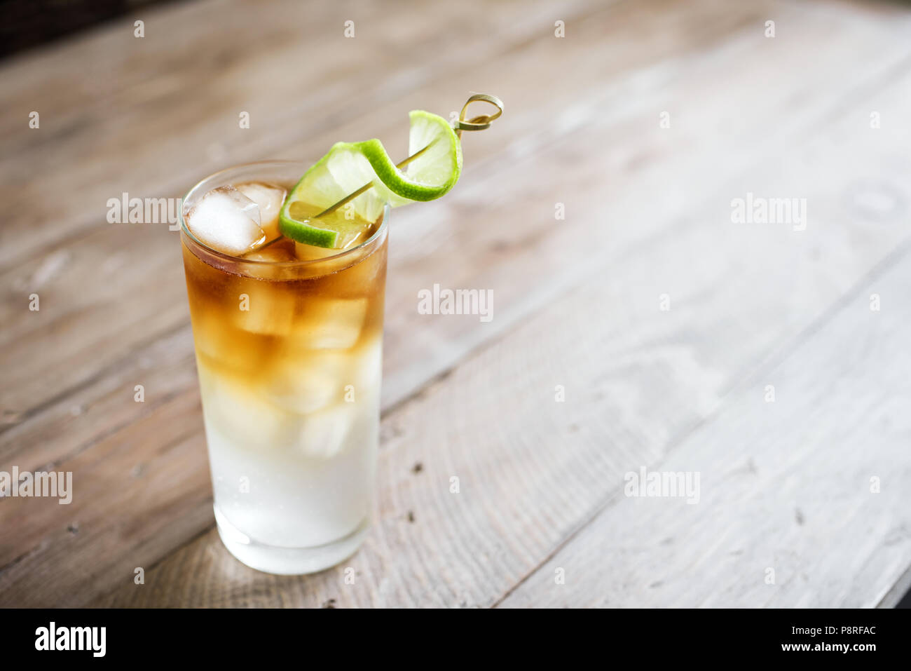 Dark and Stormy Rum Cocktail with Ginger Beer and Lime garnish. Glass of Dark and Stormy Cocktail drink on wooden table, copy space. Stock Photo