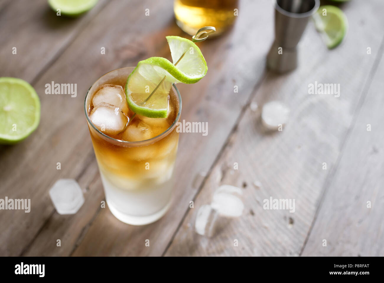 Dark and Stormy Rum Cocktail with Ginger Beer and Lime garnish. Glass of Dark and Stormy Cocktail drink on wooden table, copy space. Stock Photo