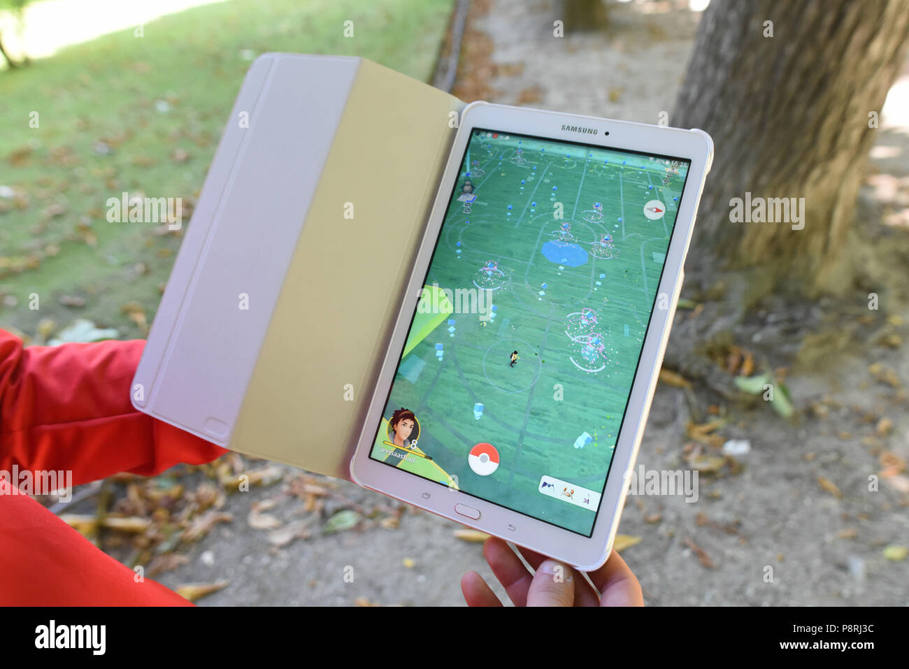 July 14, 2016 - Paris, France: A player shows the map on his tablet as he takes part in a mass Pokemon hunt in the Luxembourg Garden in central Paris. Hundreds of players of the new Pokemon Go game showed up to take part in a massive hunt despite the authorities' attempt to cancel the event. Despite playing mostly solo, the Pokemon Go users enjoyed to interact and meet other players. Millions of users have already downloaded the game, which requires users to catch on-screen pokemon characters using their real-world location.  Des jeunes participent a une chasse au Pokemons dans le jardin du Lu Stock Photo