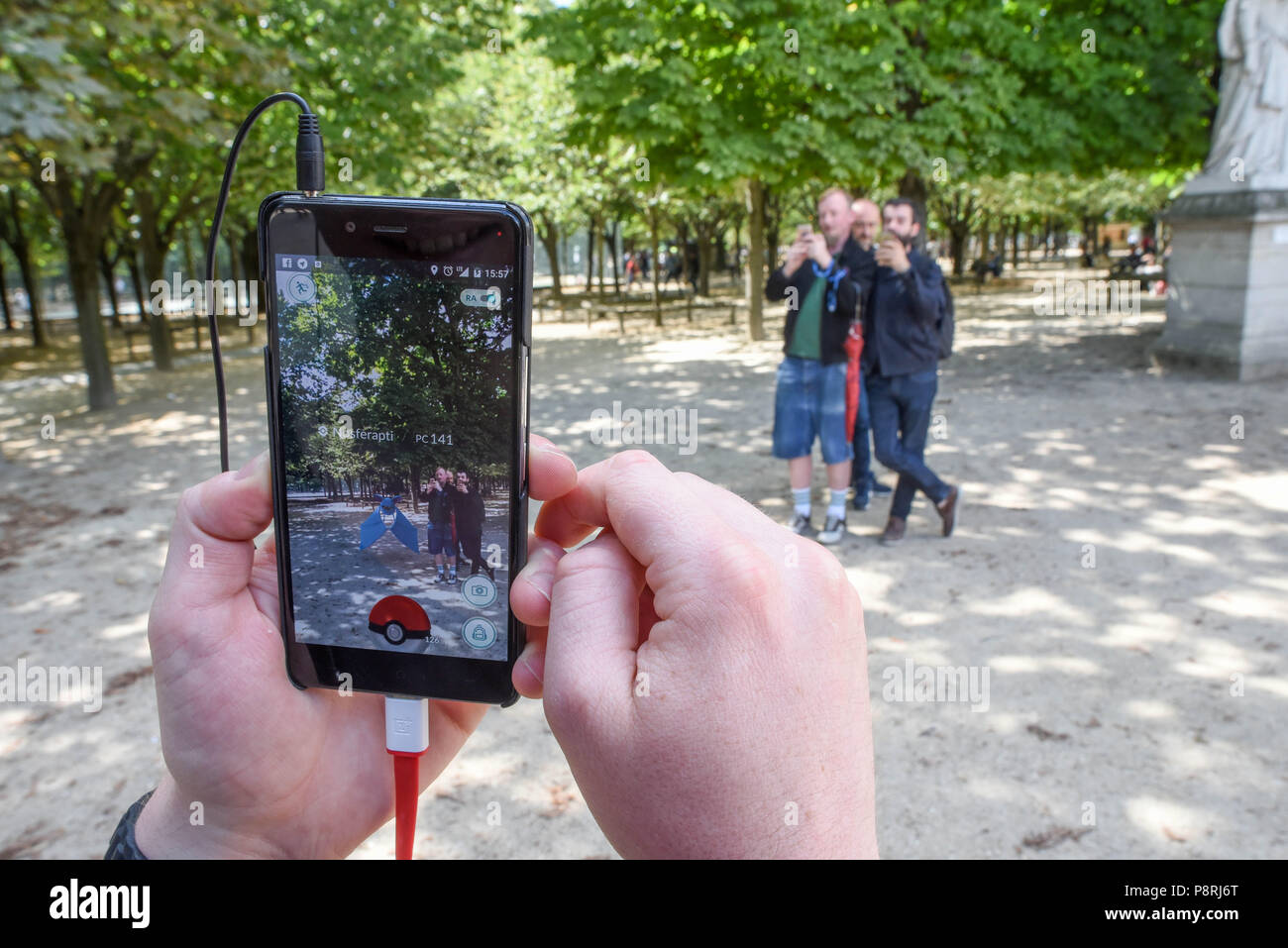 July 14, 2016 - Paris, France: Youths take part in a mass Pokemon hunt in the Luxembourg Garden in central Paris. Hundreds of players of the new Pokemon Go game showed up to take part in a massive hunt despite the authorities' attempt to cancel the event. Despite playing mostly solo, the Pokemon Go users enjoyed to interact and meet other players. Millions of users have already downloaded the game, which requires users to catch on-screen pokemon characters using their real-world location.  Des jeunes participent a une chasse au Pokemons dans le jardin du Luxembourg avec l'application Pokemon G Stock Photo