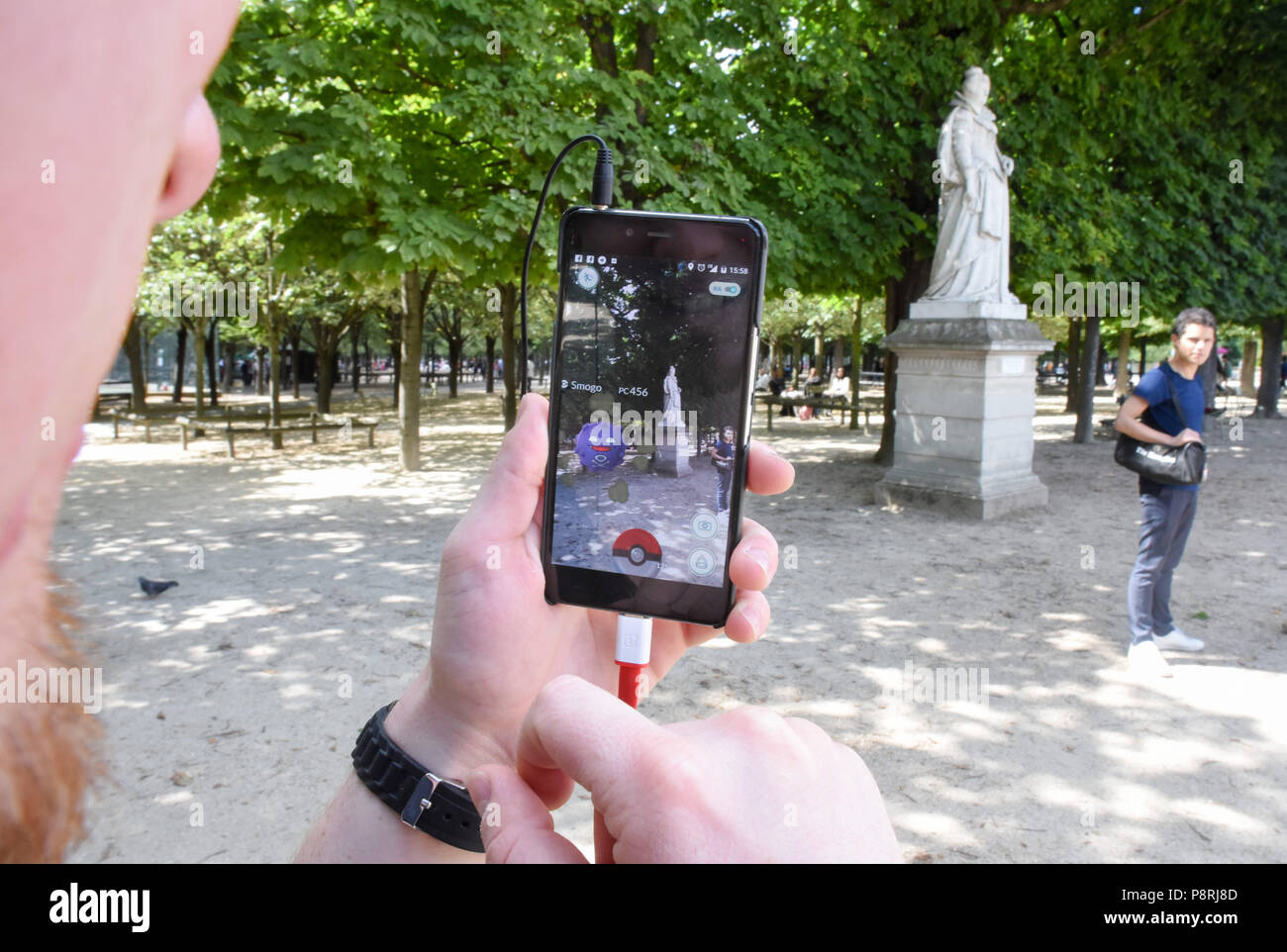 July 14, 2016 - Paris, France: Youths take part in a mass Pokemon hunt in the Luxembourg Garden in central Paris. Hundreds of players of the new Pokemon Go game showed up to take part in a massive hunt despite the authorities' attempt to cancel the event. Despite playing mostly solo, the Pokemon Go users enjoyed to interact and meet other players. Millions of users have already downloaded the game, which requires users to catch on-screen pokemon characters using their real-world location.  Des jeunes participent a une chasse au Pokemons dans le jardin du Luxembourg avec l'application Pokemon G Stock Photo