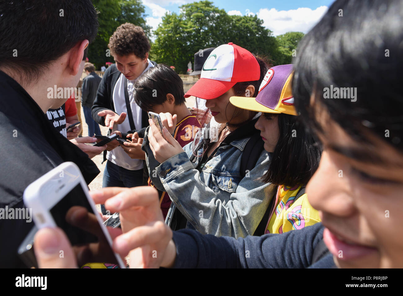 July 14, 2016 - Paris, France: Youths take part in a mass Pokemon hunt in the Luxembourg Garden in central Paris. Hundreds of players of the new Pokemon Go game showed up to take part in a massive hunt despite the authorities' attempt to cancel the event. Despite playing mostly solo, the Pokemon Go users enjoyed to interact and meet other players. Millions of users have already downloaded the game, which requires users to catch on-screen pokemon characters using their real-world location.  Des jeunes participent a une chasse au Pokemons dans le jardin du Luxembourg avec l'application Pokemon G Stock Photo