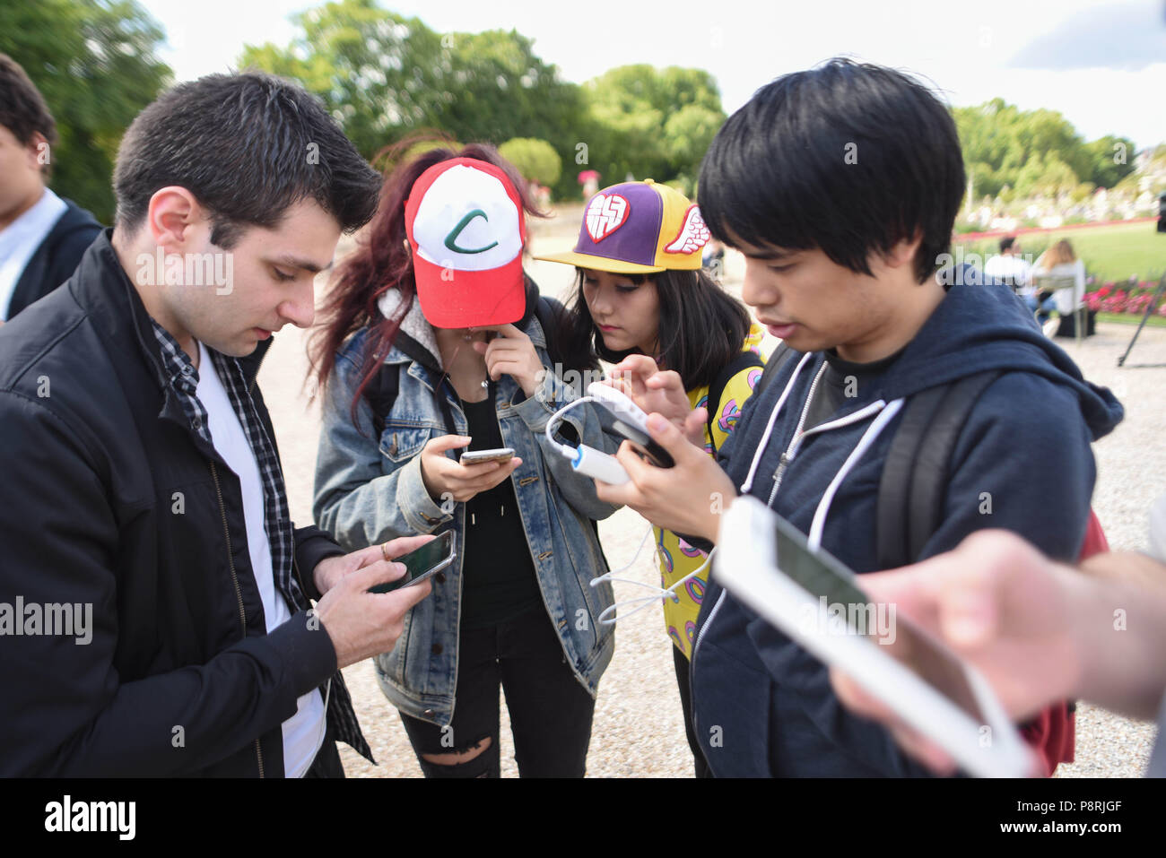 July 14, 2016 - Paris, France: Youths take part in a mass Pokemon hunt in the Luxembourg Garden in central Paris. Hundreds of players of the new Pokemon Go game showed up to take part in a massive hunt despite the authorities' attempt to cancel the event. Despite playing mostly solo, the Pokemon Go users enjoyed to interact and meet other players. Millions of users have already downloaded the game, which requires users to catch on-screen pokemon characters using their real-world location.  Des jeunes participent a une chasse au Pokemons dans le jardin du Luxembourg avec l'application Pokemon G Stock Photo