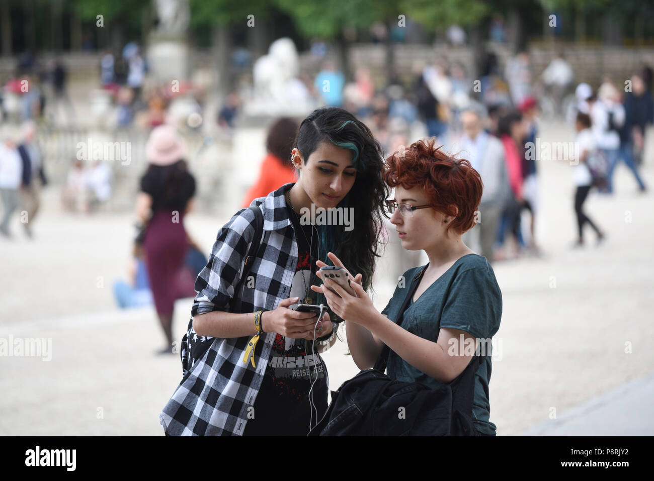 July 14, 2016 - Paris, France: French arts students Calypso (L), 17 yo, and Lorenz, 18yo, take part in a mass Pokemon hunt in the Luxembourg Garden in central Paris. Hundreds of players of the new Pokemon Go game showed up to take part in a massive hunt despite the authorities' attempt to cancel the event. Despite playing mostly solo, the Pokemon Go users enjoyed to interact and meet other players. Millions of users have already downloaded the game, which requires users to catch on-screen pokemon characters using their real-world location.  Des jeunes participent a une chasse au Pokemons dans  Stock Photo