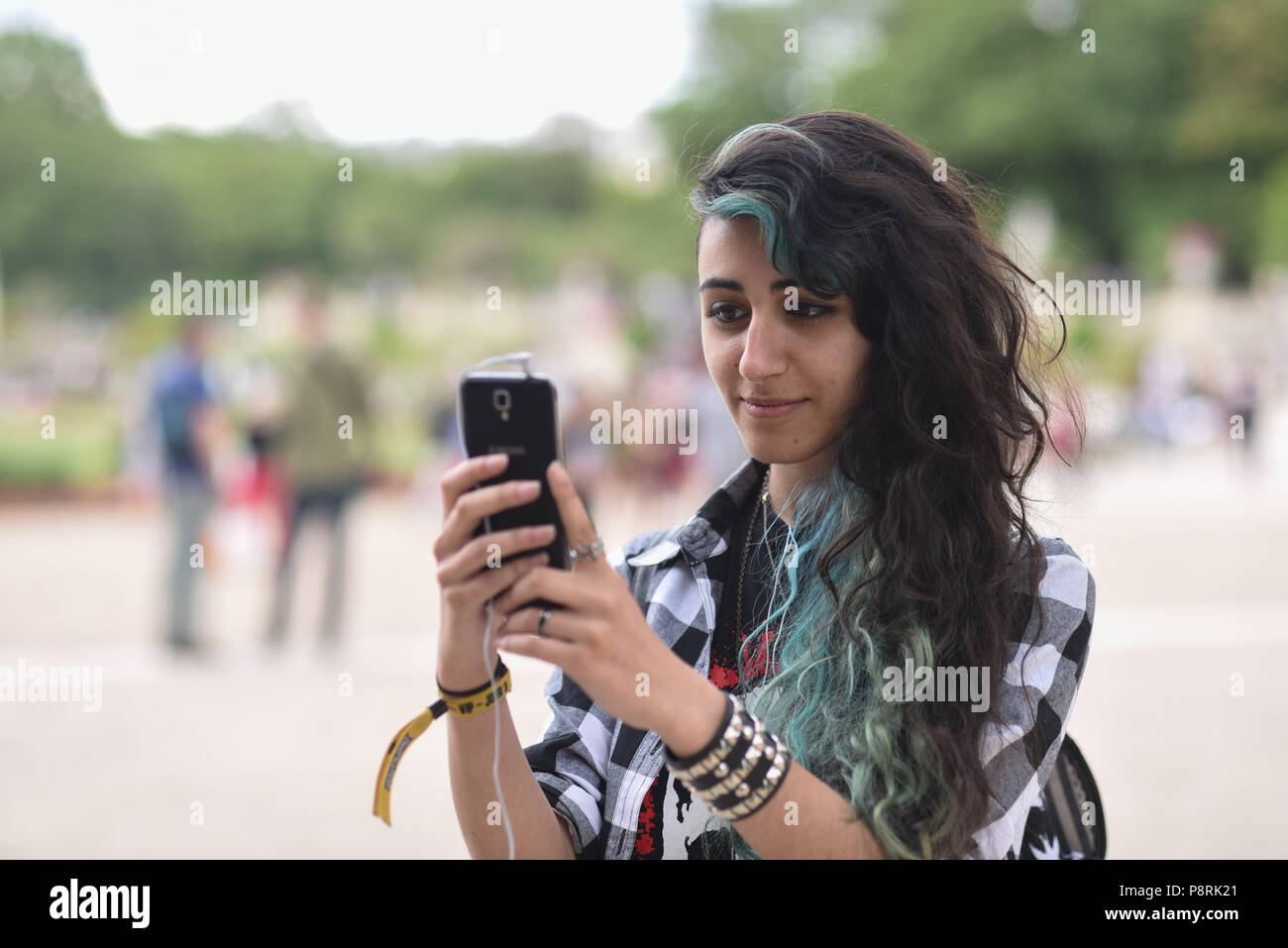 July 14, 2016 - Paris, France: French arts students Calypso, 17 yo, takes part in a mass Pokemon hunt in the Luxembourg Garden in central Paris. Hundreds of players of the new Pokemon Go game showed up to take part in a massive hunt despite the authorities' attempt to cancel the event. Despite playing mostly solo, the Pokemon Go users enjoyed to interact and meet other players. Millions of users have already downloaded the game, which requires users to catch on-screen pokemon characters using their real-world location.  Des jeunes participent a une chasse au Pokemons dans le jardin du Luxembou Stock Photo