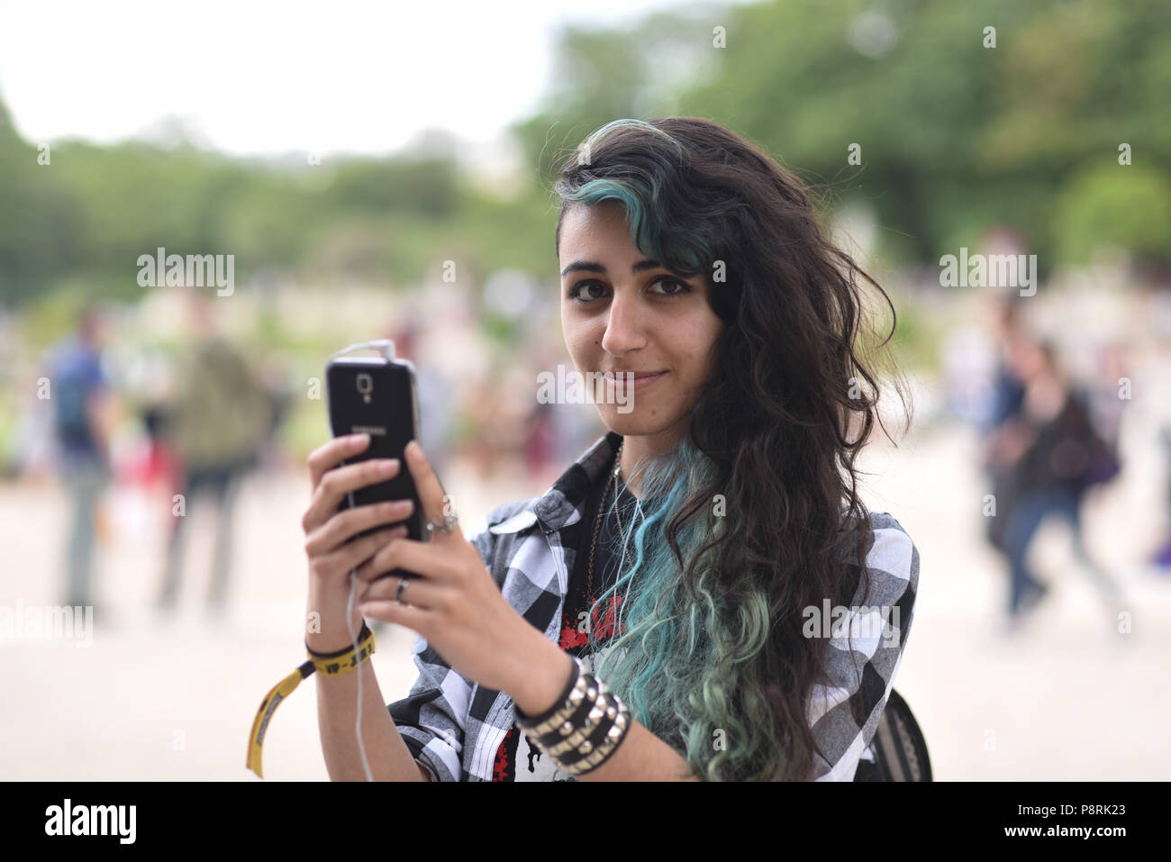 July 14, 2016 - Paris, France: French arts students Calypso, 17 yo, takes part in a mass Pokemon hunt in the Luxembourg Garden in central Paris. Hundreds of players of the new Pokemon Go game showed up to take part in a massive hunt despite the authorities' attempt to cancel the event. Despite playing mostly solo, the Pokemon Go users enjoyed to interact and meet other players. Millions of users have already downloaded the game, which requires users to catch on-screen pokemon characters using their real-world location. Des jeunes participent a une chasse au Pokemons dans le jardin du Luxembour Stock Photo