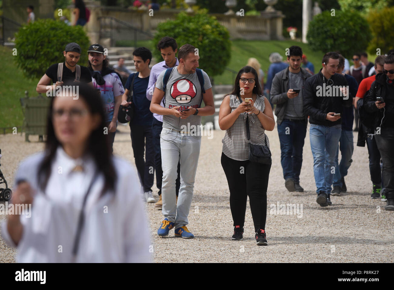 July 14, 2016 - Paris, France: Youths take part in a mass Pokemon hunt in the Luxembourg Garden in central Paris. Hundreds of players of the new Pokemon Go game showed up to take part in a massive hunt despite the authorities' attempt to cancel the event. Despite playing mostly solo, the Pokemon Go users enjoyed to interact and meet other players. Millions of users have already downloaded the game, which requires users to catch on-screen pokemon characters using their real-world location.  Des jeunes participent a une chasse au Pokemons dans le jardin du Luxembourg avec l'application Pokemon G Stock Photo