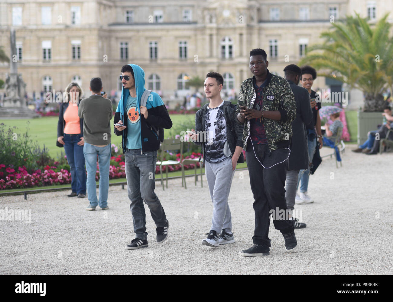 July 14, 2016 - Paris, France: Youths take part in a mass Pokemon hunt in the Luxembourg Garden in central Paris. Hundreds of players of the new Pokemon Go game showed up to take part in a massive hunt despite the authorities' attempt to cancel the event. Despite playing mostly solo, the Pokemon Go users enjoyed to interact and meet other players. Millions of users have already downloaded the game, which requires users to catch on-screen pokemon characters using their real-world location. Des jeunes participent a une chasse au Pokemons dans le jardin du Luxembourg avec l'application Pokemon Go Stock Photo