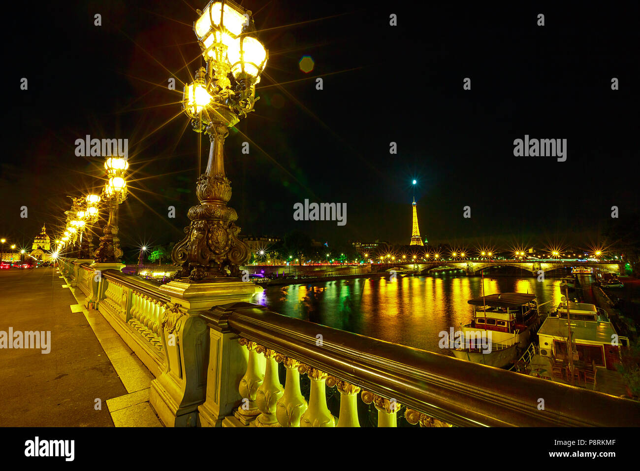 Paris lights on in Pont Alexandre III bridge with lighted lamps. French European capital with Eiffel Tower and Paris night skyline in France. Night urban scene. Stock Photo