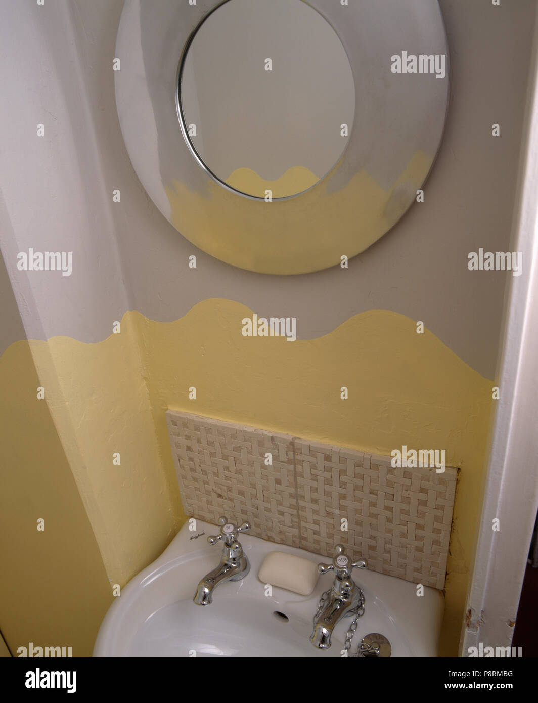 detail of decoration in small yellow and grey painted cloakroom with circular mirror Stock Photo