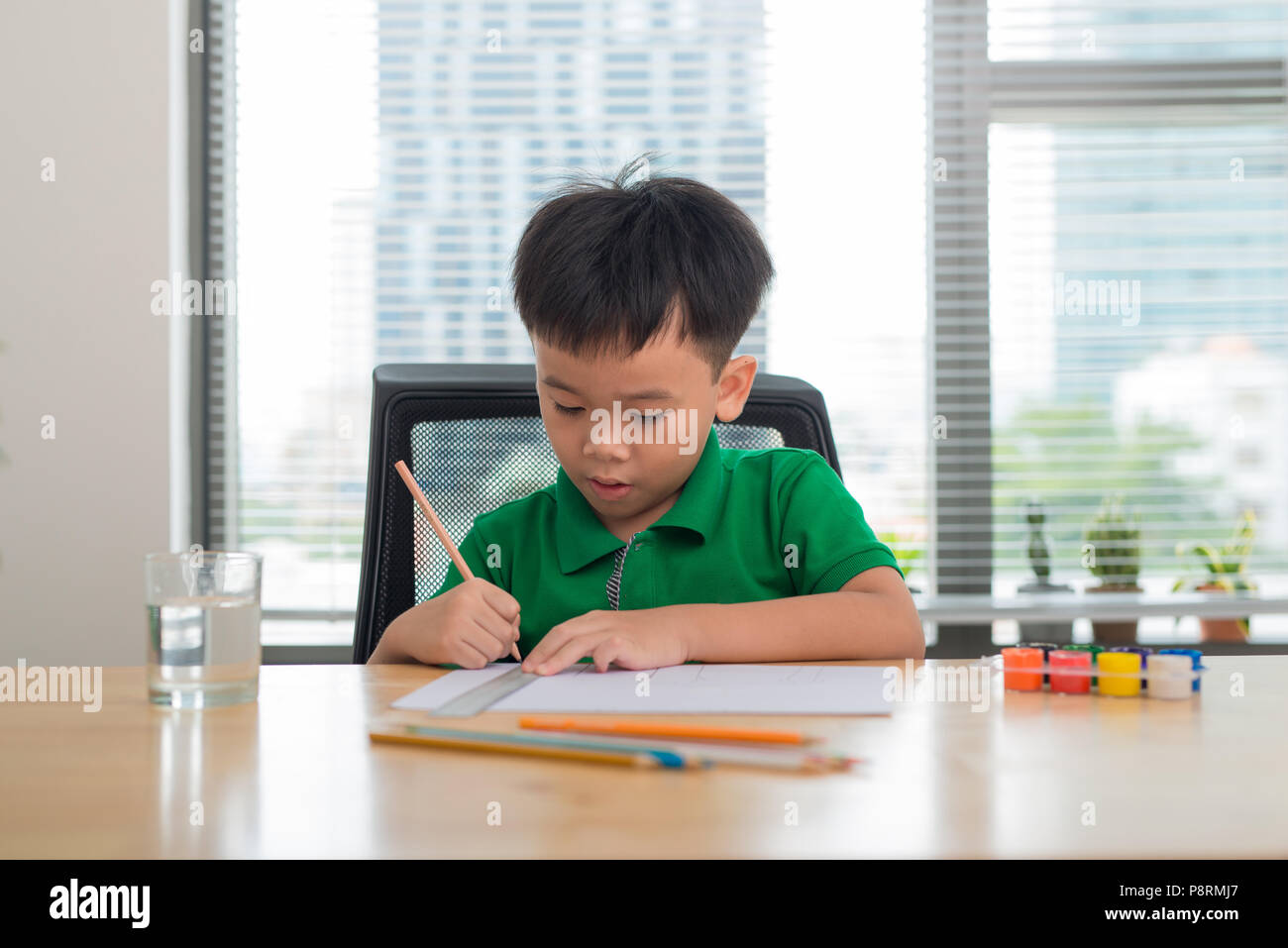 Cute boy is drawing using color pencils, isolated over white Stock Photo