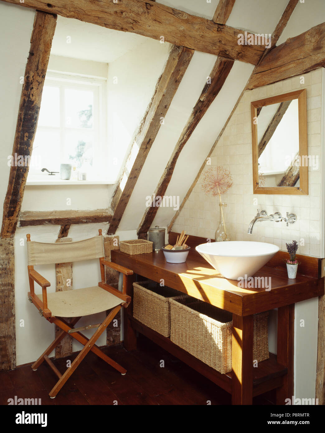 Contemporary basin unit and folding chair in white beamed bathroom under eaves of a period conversion Stock Photo