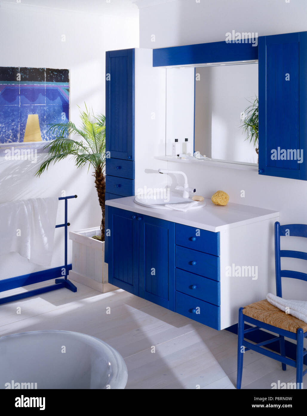 Mirror In Blue Fitted Cabinet Above White Sink In Bluewhite Vanity Unit In Economy Style Bathroom With Painted Wood Floor
