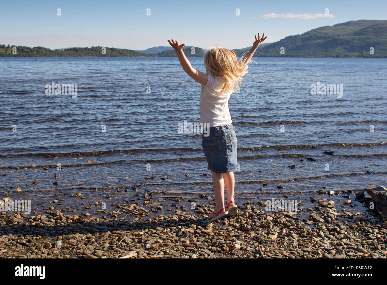 Very happy young girl jumping on Loch Lomond Beach Stock Photo