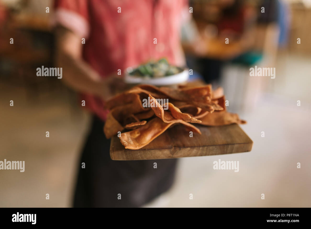Waiter holding a serving board of freshly baked nachos  Stock Photo