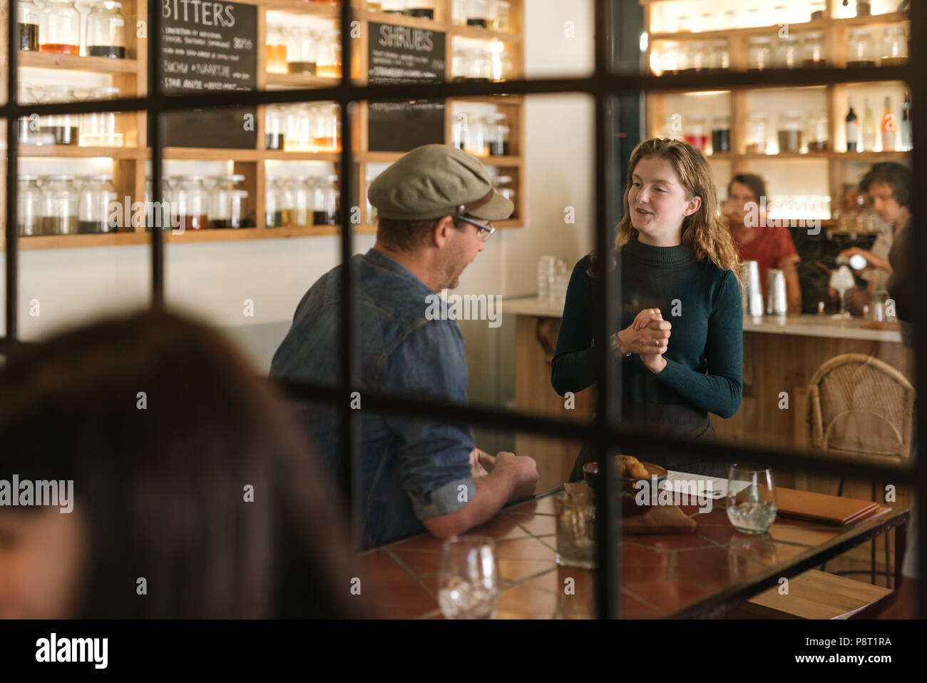 Smiling young waitress talking with a bistro customer Stock Photo