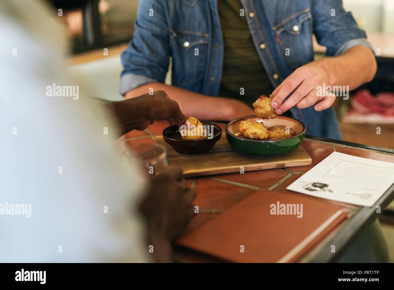 Two men sitting at a bistro table sharing delicious food  Stock Photo
