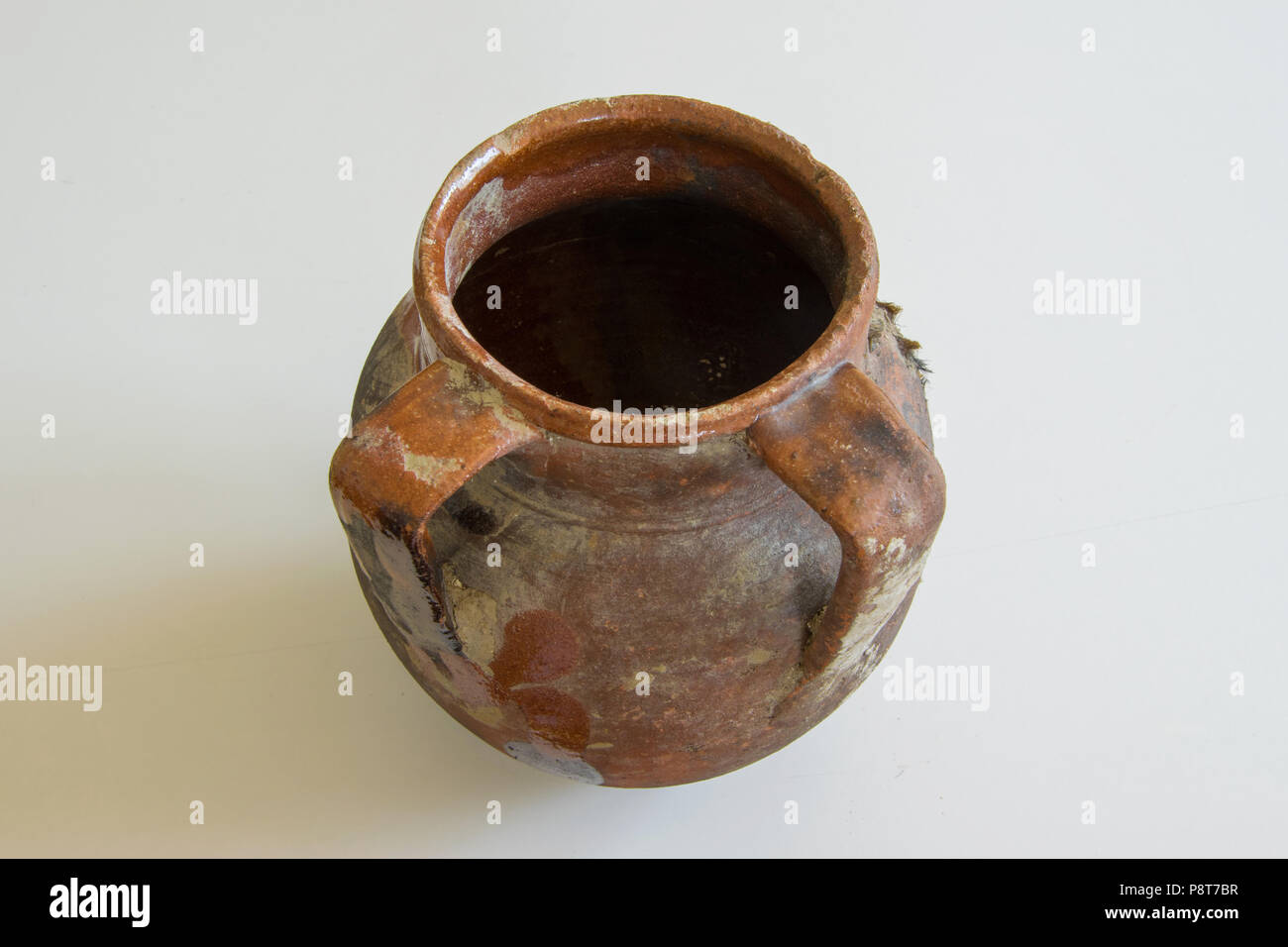 Antique handmade ceramic vase with two handles on white background