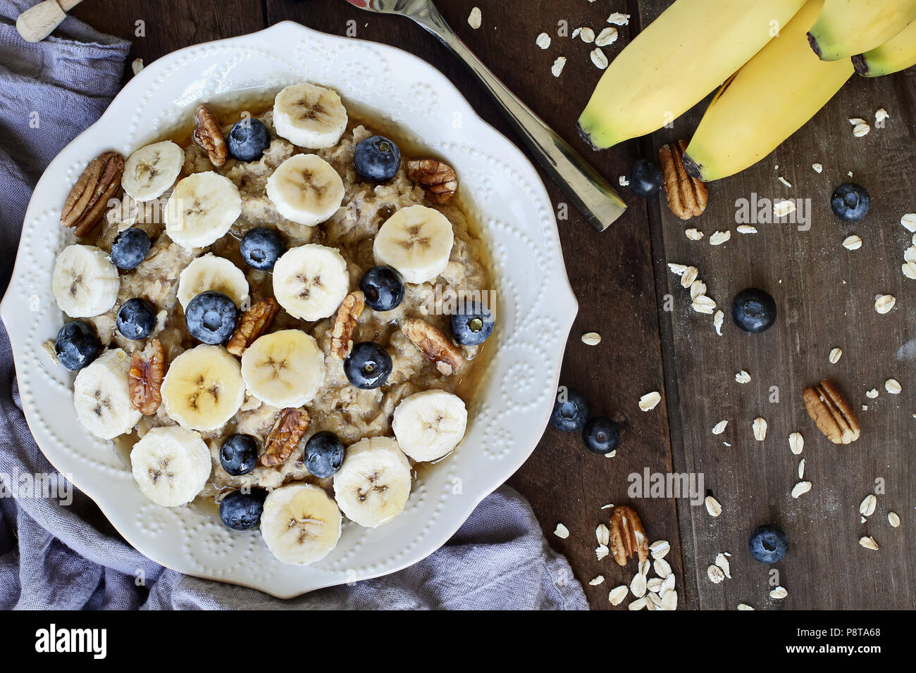 Hot breakfast of healthy oatmeal with pecans, bananas, blueberries and