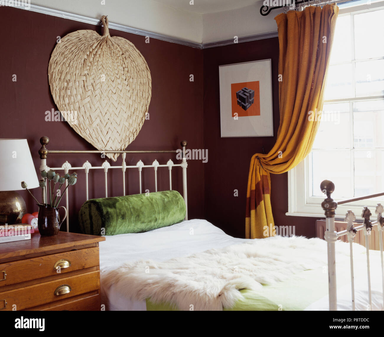 Large Palm Leaf Fan On Wall Above Brass Bed In Brown Bedroom