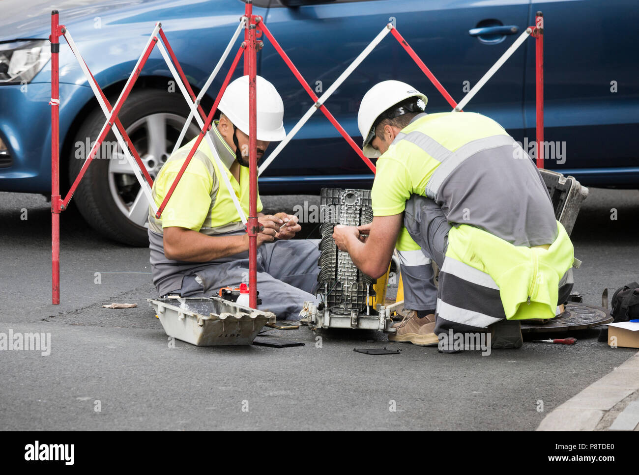 TelephTelephone engineers working on fibre optic cables on busy road in