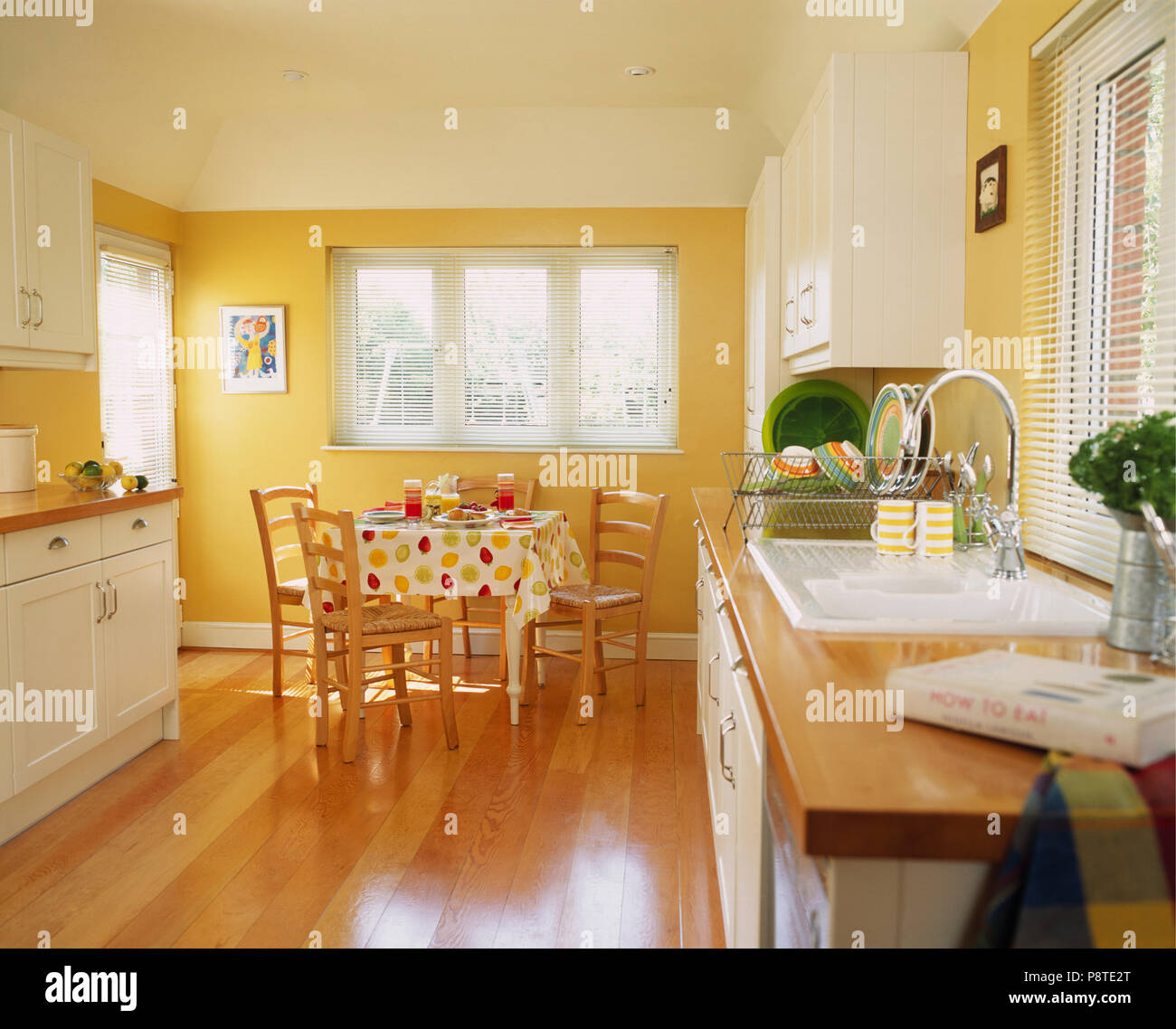 Wooden Flooring In Modern Yellow Kitchen With Fitted White