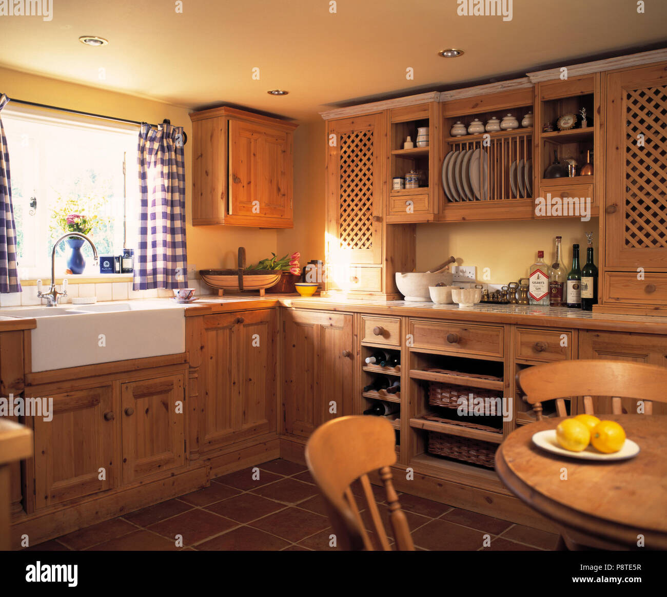 Blue White Checked Curtains Above White Ceramic Sink In Cottage Kitchen With Fitted Wooden Cupboards Stock Photo Alamy