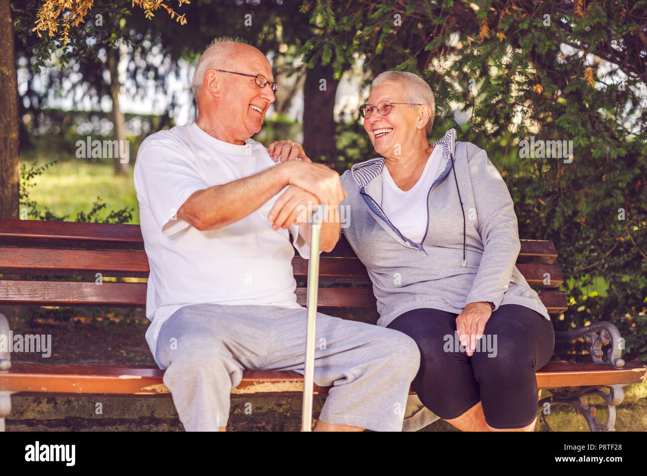 Smiling senior couple sitting together on a park bench Stock Photo - Alamy