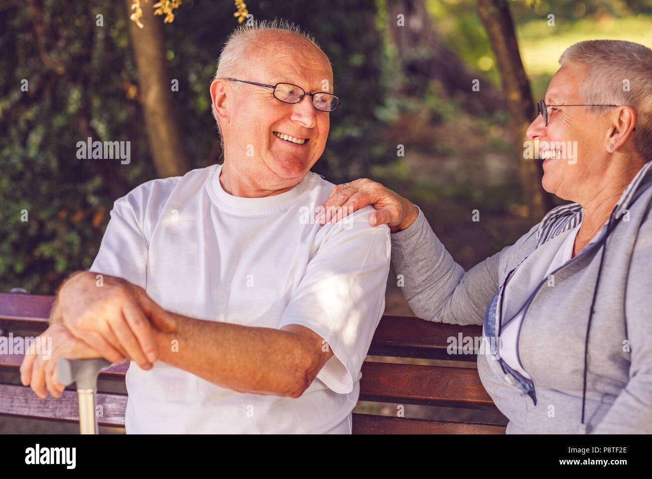 Happy together. Smiling senior couple sitting together on a park bench Stock Photo