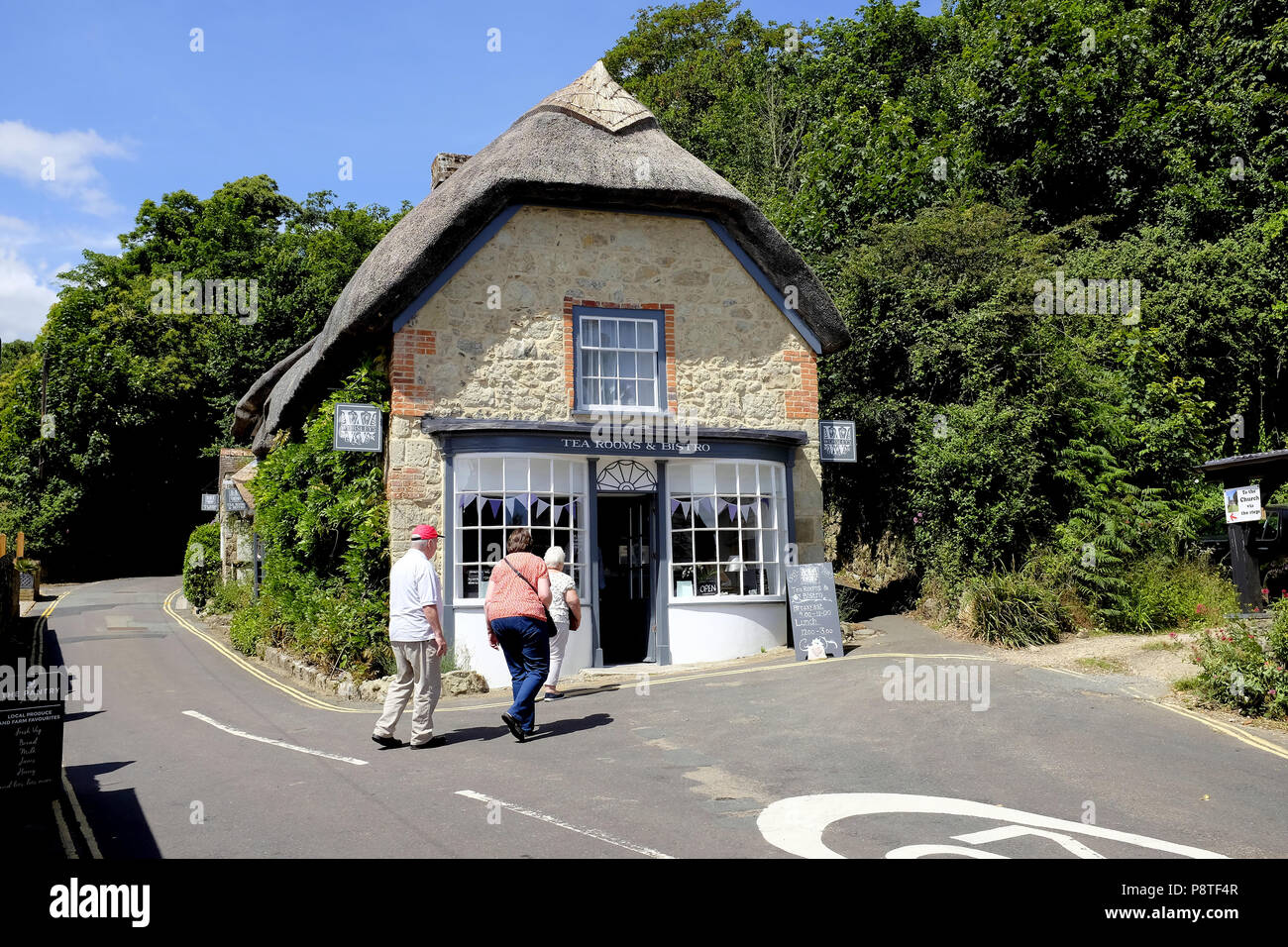 Godshill, Isle of Wight, UK. June 21, 2018.  Three senior holidaymakers walking towards a thatched tea rooms in the village of Godshill on the Isle of Stock Photo