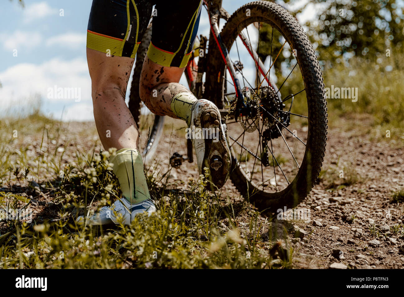 back dirty feet mountain biker climbs uphill with bicycle Stock Photo