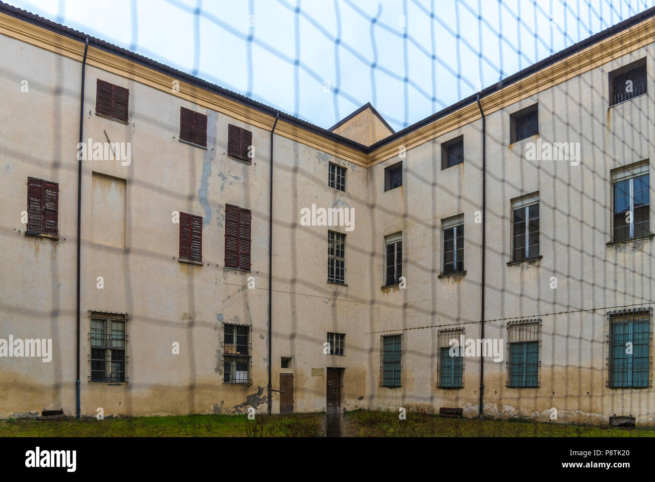 Abandoned prison shot behind rusted chain link fence Stock Photo