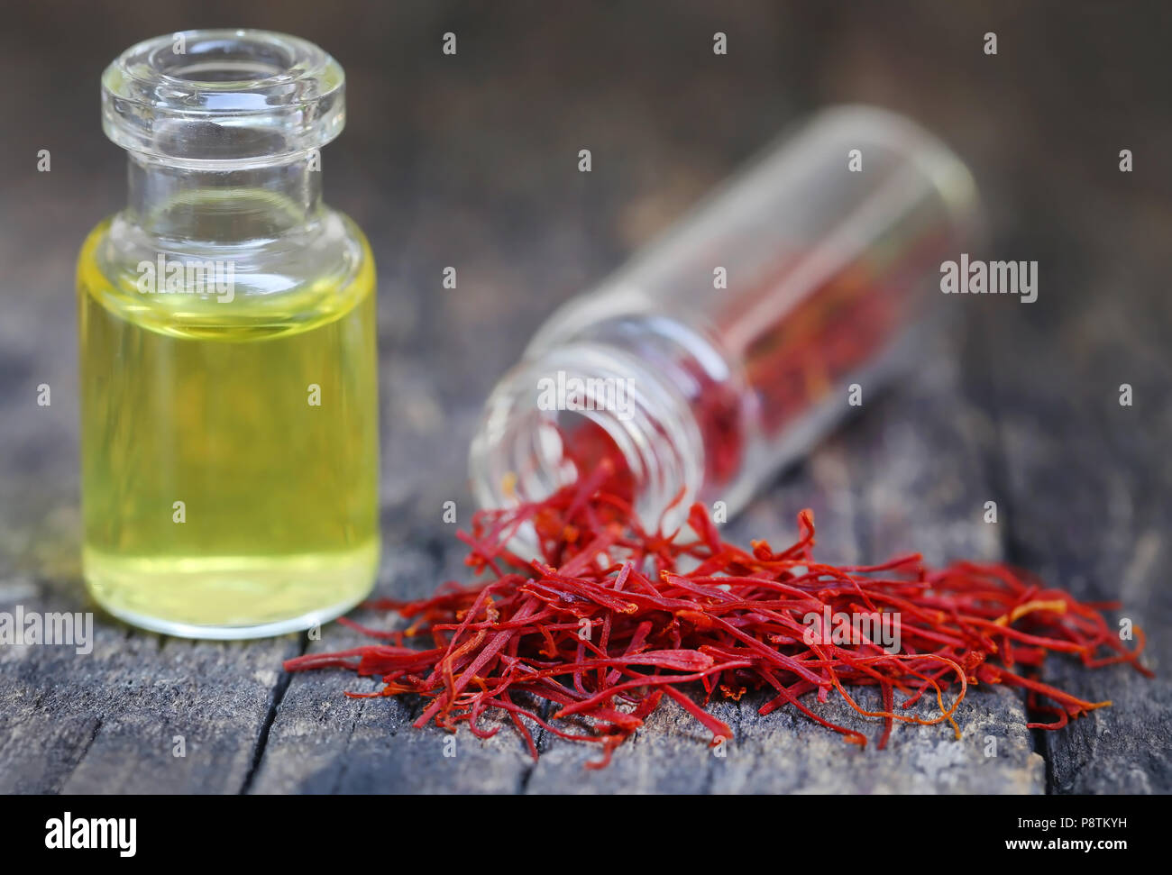 Closeup of Saffron with extract in a bottle on natural surface Stock Photo