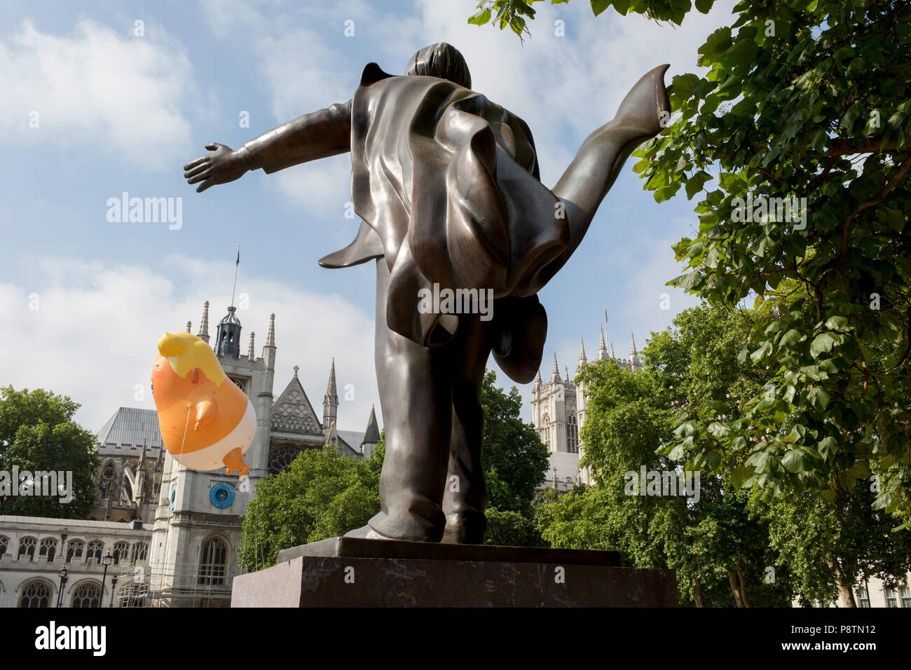 London, UK. 13th July, 2018. The inflatable balloon called Baby Trump flies above the statue of British statesman David Lloyd George in Parliament Square, Westminster, the seat of the UK Parliament, during the US President's visit to the UK. Baby Trump is a 20ft high orange blimp depicting the US President as an enraged, smartphone-clutching infant - and given special permission to appear above the capital by London Mayor Sadiq Khan because of its protest rather than artistic nature. It is the brainchild of Graphic designer Matt Bonner. Photo by Richard B Credit: RichardBaker/Alamy Live News Stock Photo