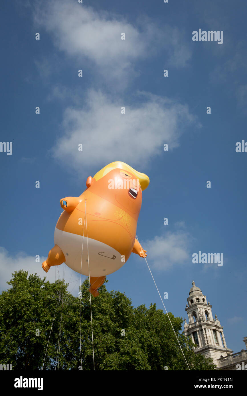 London, UK. 13th July, 2018. The inflatable balloon called Baby Trump flies above Parliament Square in Westminster, the seat of the UK Parliament, during the US President's visit to the UK. Baby Trump is a 20ft high orange blimp depicting the US President as an enraged, smartphone-clutching infant - and given special permission to appear above the capital by London Mayor Sadiq Khan because of its protest rather than artistic nature. It is the brainchild of Graphic designer Matt Bonner. Credit: RichardBaker/Alamy Live News Stock Photo