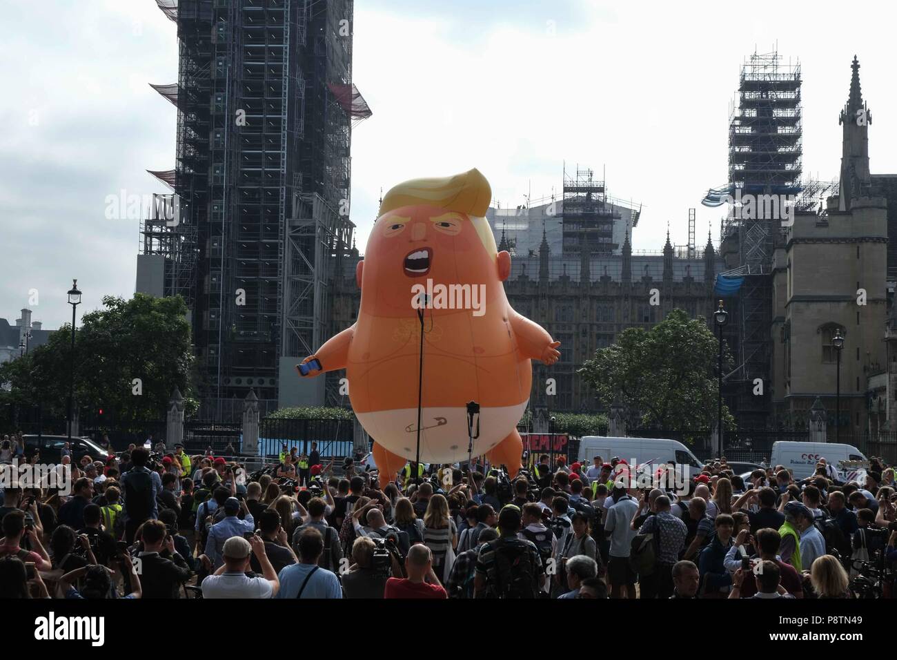 London 13th July 2018: A six metre high helium filled inflatable of President Trump depicted as a giant angry orange baby  wearing a nappie is raised over Parliament Square by activist protesting  his visit to the UK. Credit: Claire Doherty/Alamy Live News Stock Photo