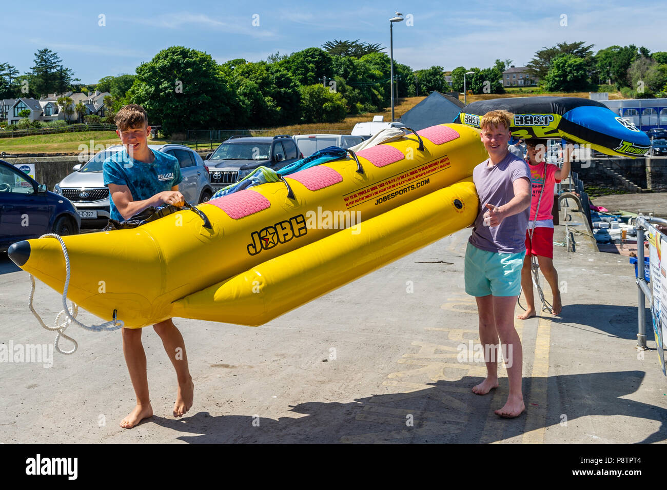 Schull, West Cork, Ireland. 13th July, 2018. Making the most of the hot weather and preparing to have some fun on towable inflatables in the water in Schull Harbour are Jamie Donnelly, Tom Casey and Jeremy Kingston, all from Cork city. The rest of the day will have highs of 20° Celsius but the rest of the weekend will be cooler with rain forecast for Sunday. Credit: Andy Gibson/Alamy Live News. Stock Photo