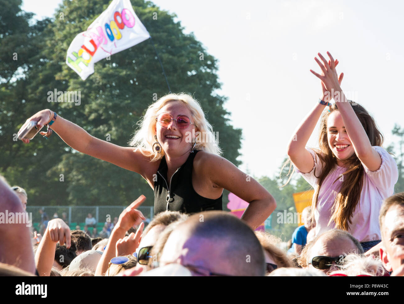 Young festival goers enjoying the music, sitting on friends shoulders in the crowd, at the Obelisk Stage at Latitude Festival, Henham Park, Suffolk, England, 13 July 2018. Stock Photo