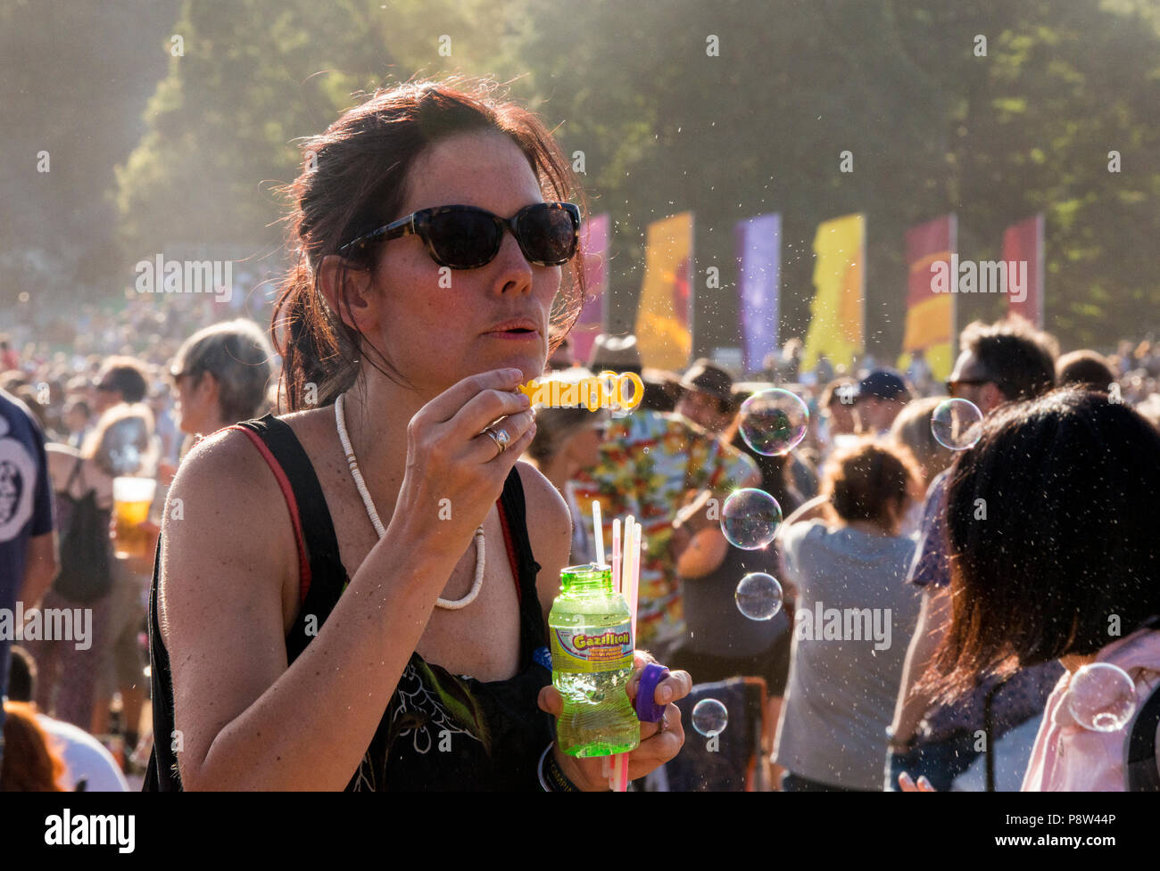 Female festival goer enjoying the music, and blowing bubbles at the Obelisk Stage at Latitude Festival, Henham Park, Suffolk, England, 13 July 2018. Stock Photo