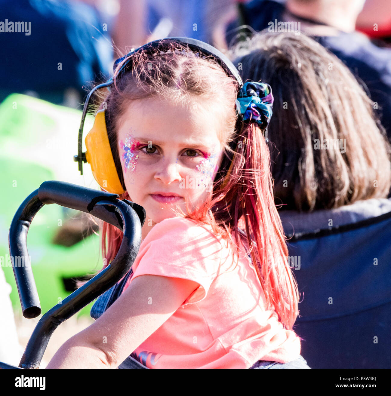 Portrait of young girl with painted face, wearing ear defenders, enjoying the atmosphere at the Obelisk Stage at Latitude Festival, Henham Park, Suffolk, England, 13 July 2018. Stock Photo