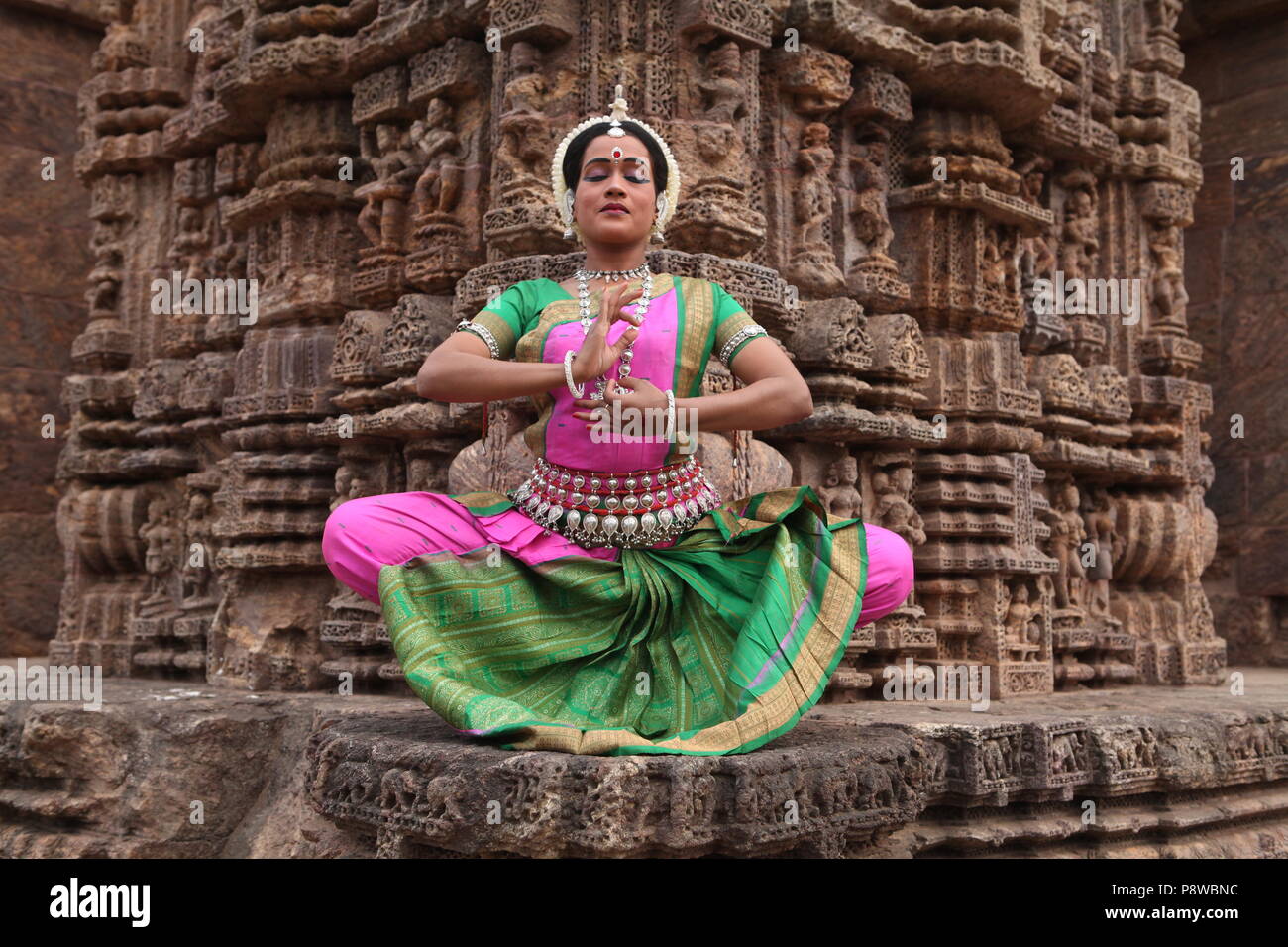 odissi is one of the eight classical dance forms of india,from the state of odisha.here the dancer poses before temples with sculptures Stock Photo