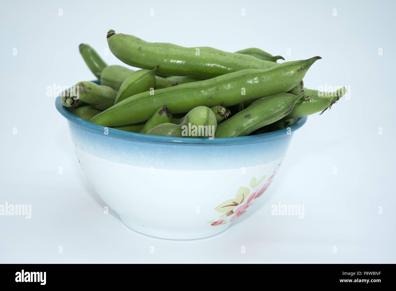 broad beans in a bowl against a white background Stock Photo