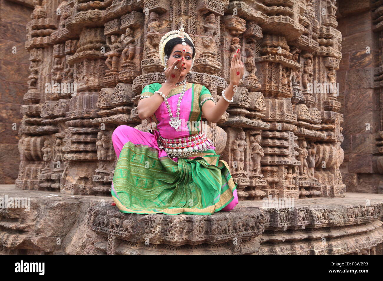 odissi is one of the eight classical dance forms of india,from the state of odisha.here the dancer poses before temples with sculptures Stock Photo