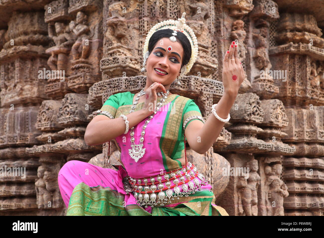 odissi is one of the eight classical dance forms of india,from the state of odisha.here the dancer poses before temples with sculptures Stock Photo