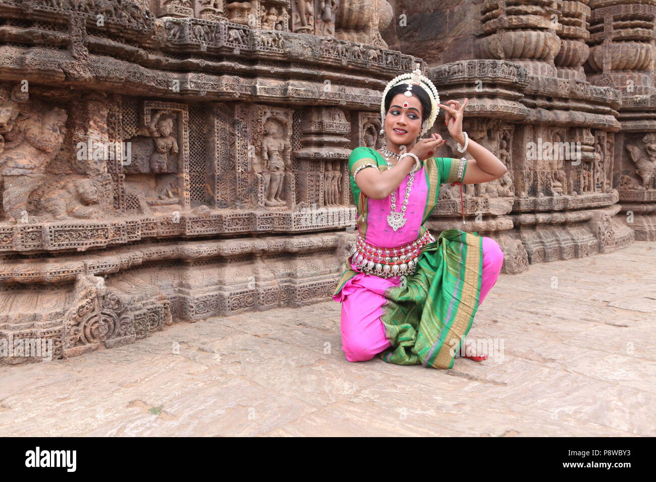 odissi is one of the eight classical dance forms of india,from the state of odisha.here the dancer poses before temples with sculptures Stock Photo