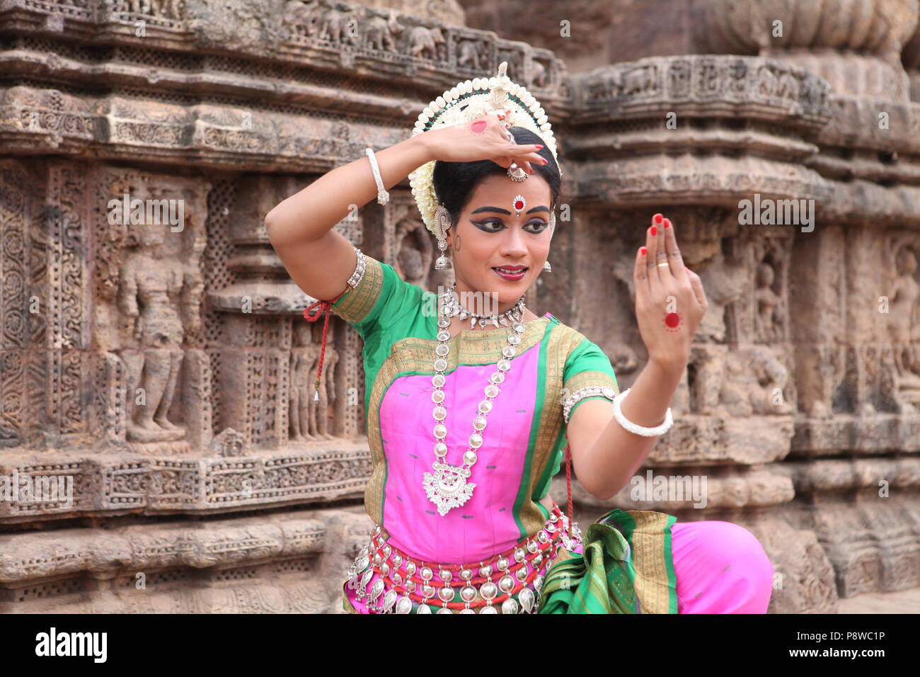 odissi is one of the eight classical dance forms of india,from the state of odisha.here the dancer poses before temples with sculptures Stock Photo