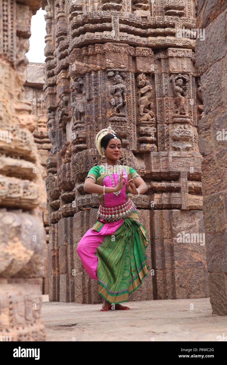odissi is one of the eight classical dance forms of india,from the state of odisha.here the dancer poses before temples with sculptures Stock Photo
