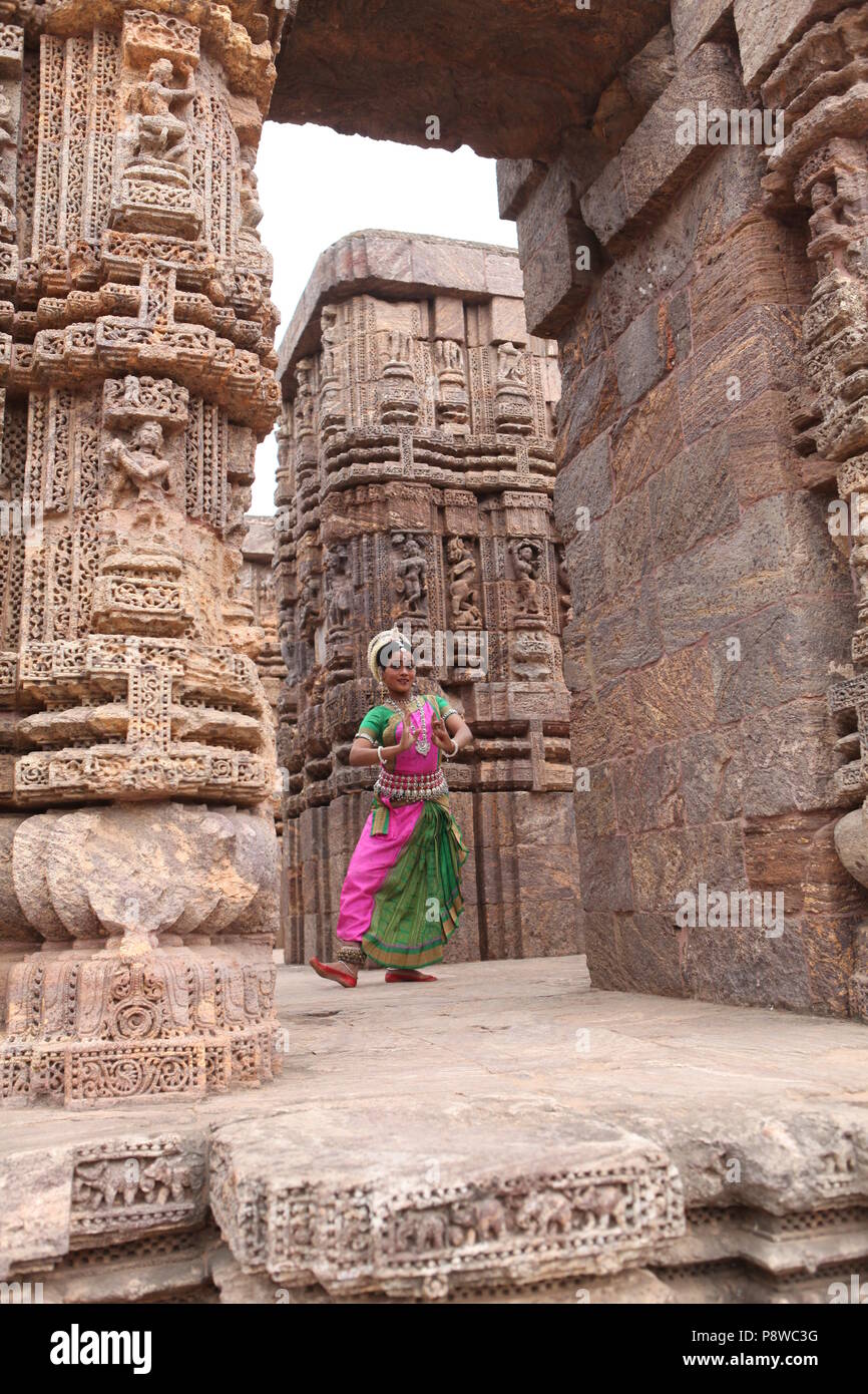 odissi is one of the eight classical dance forms of india,from the state of odisha.here the dancer poses before temples with sculptures Stock Photo