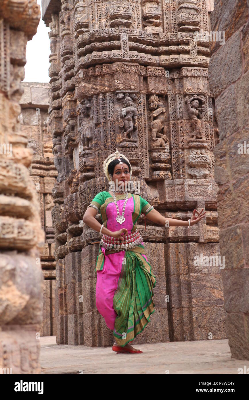 odissi is one of the eight classical dance forms of india,from the state of odisha.here the dancer poses before temples with sculptures Stock Photo